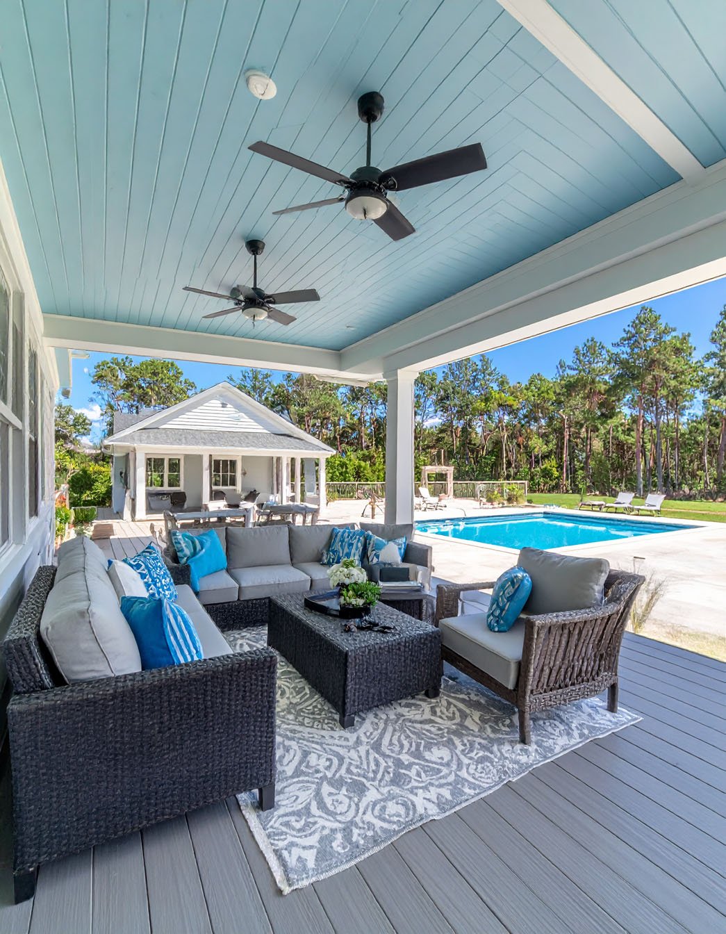 Terrasse couverte style côtier avec salon en résine tressée, vue sur piscine