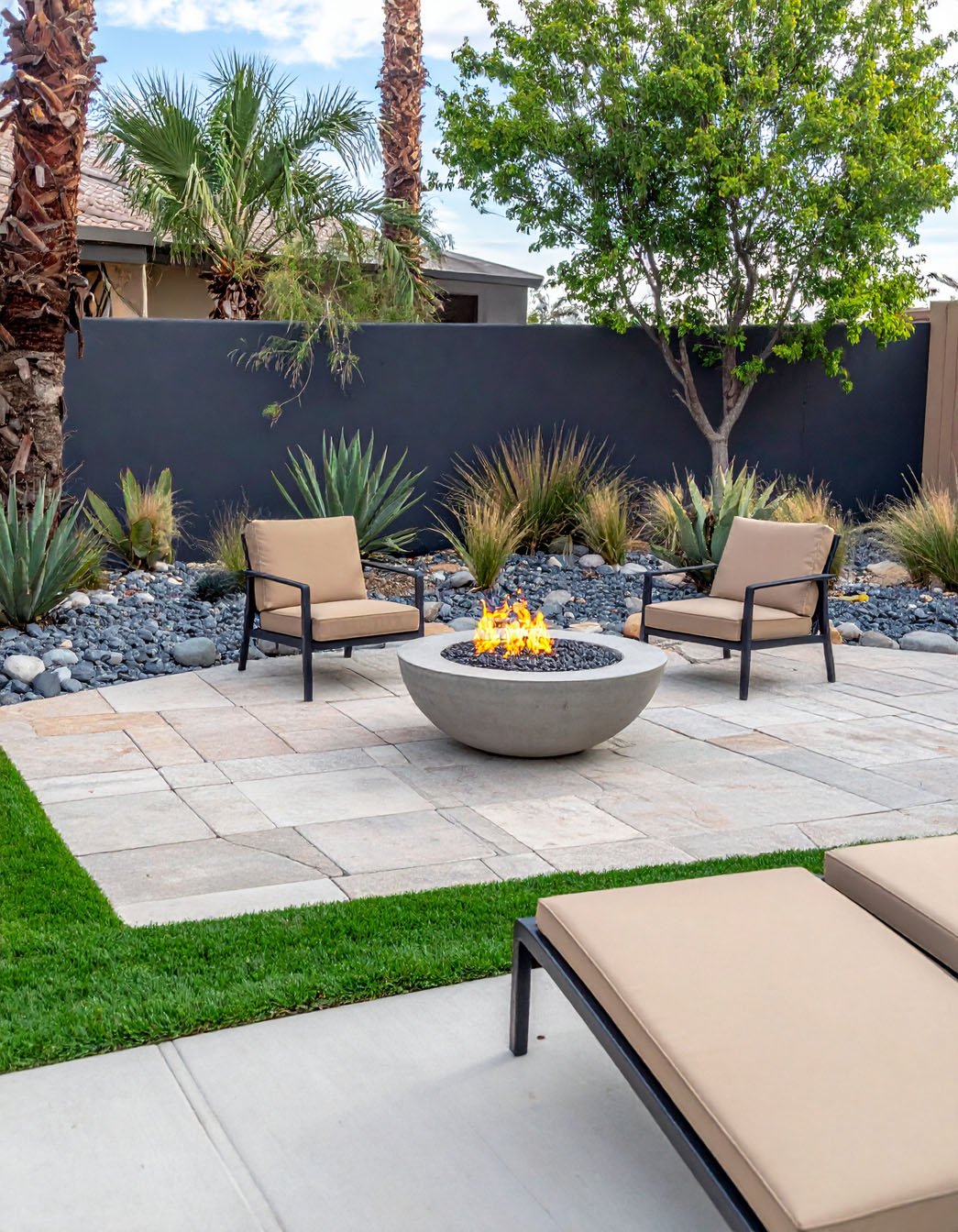 Terrasse désertique moderne avec foyer rond, fauteuils et plantes grasses