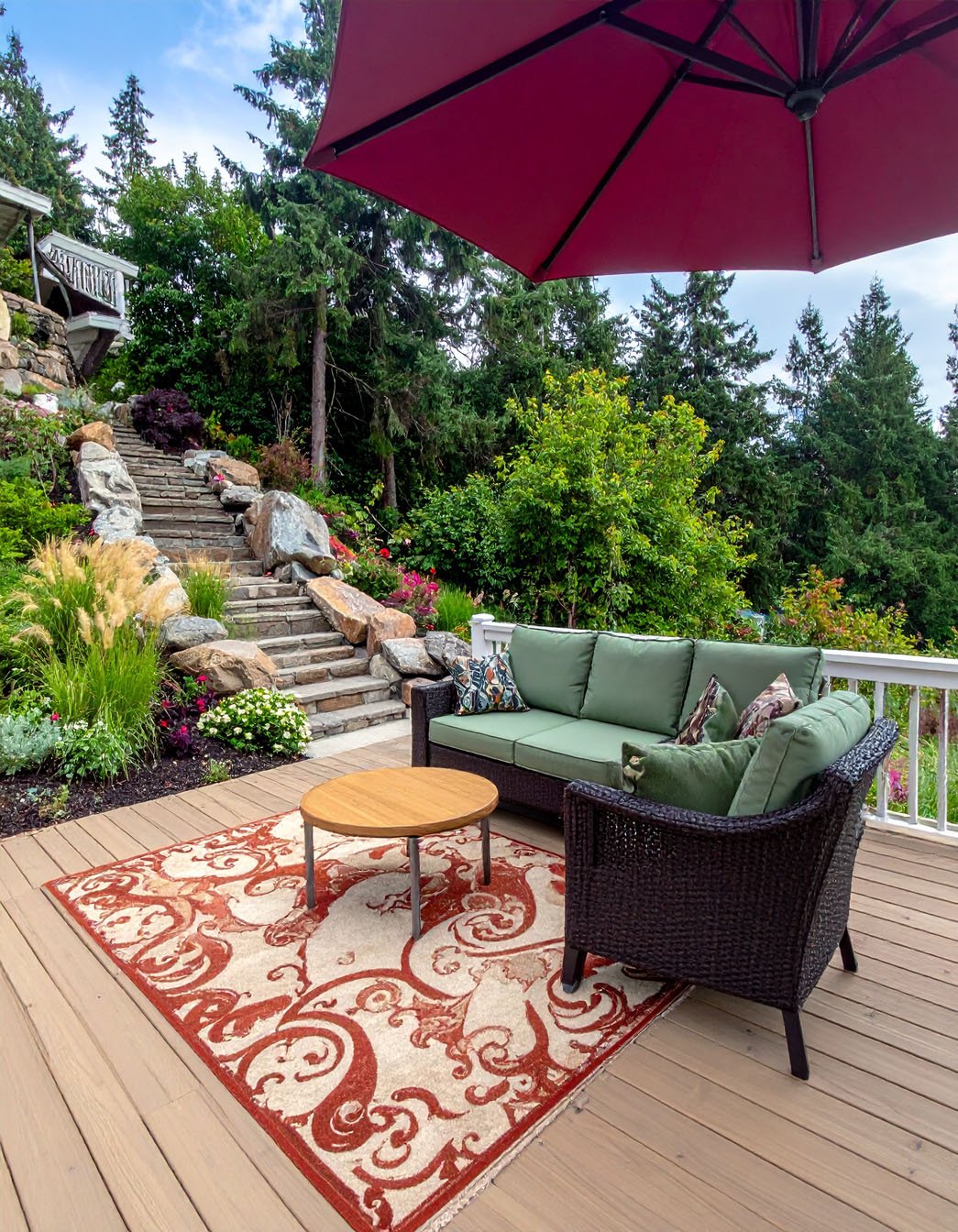 Coin lecture sur terrasse en bois avec canapé, fauteuil et parasol rouge