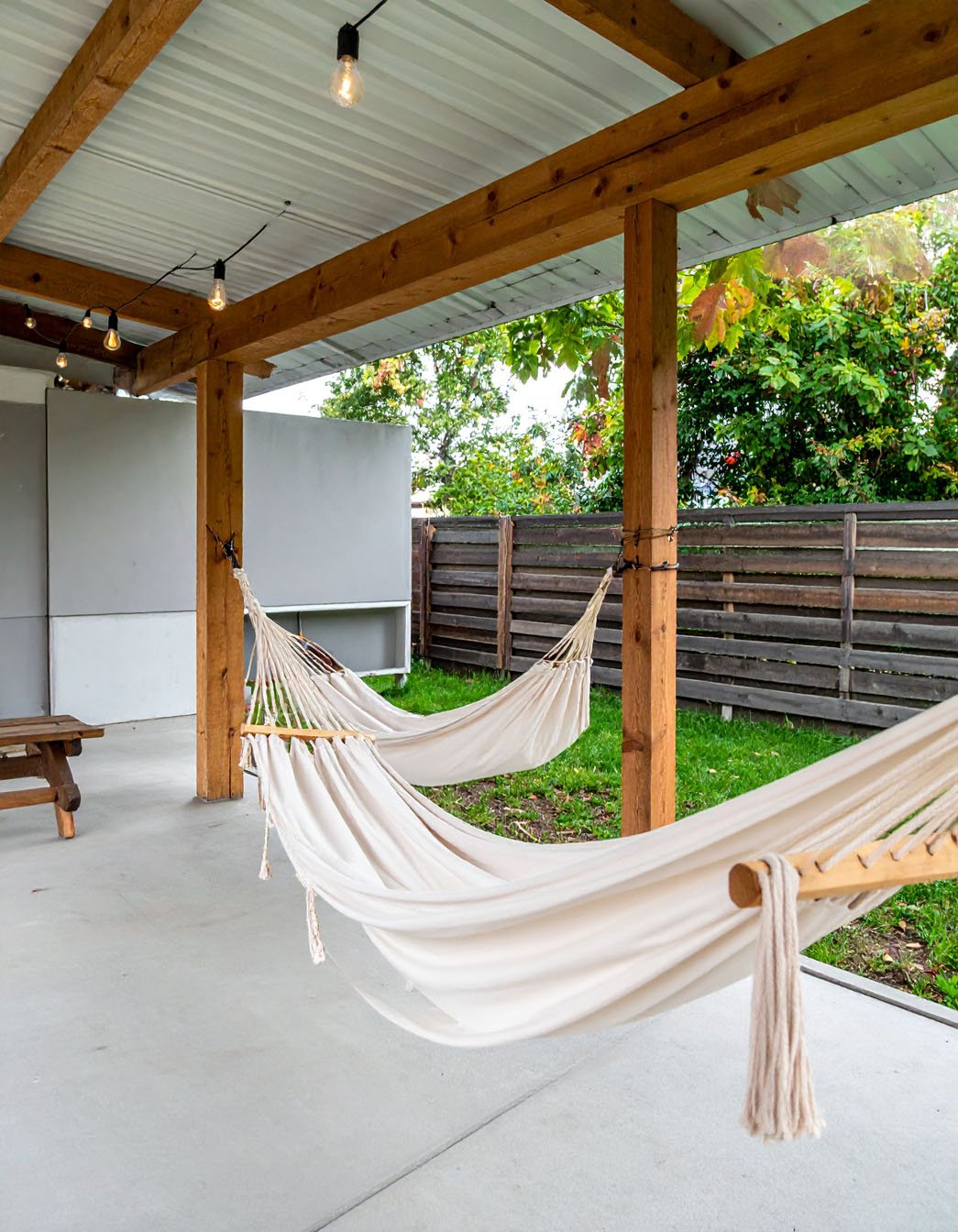 Terrasse couverte avec deux hamacs blancs suspendus à des poutres en bois