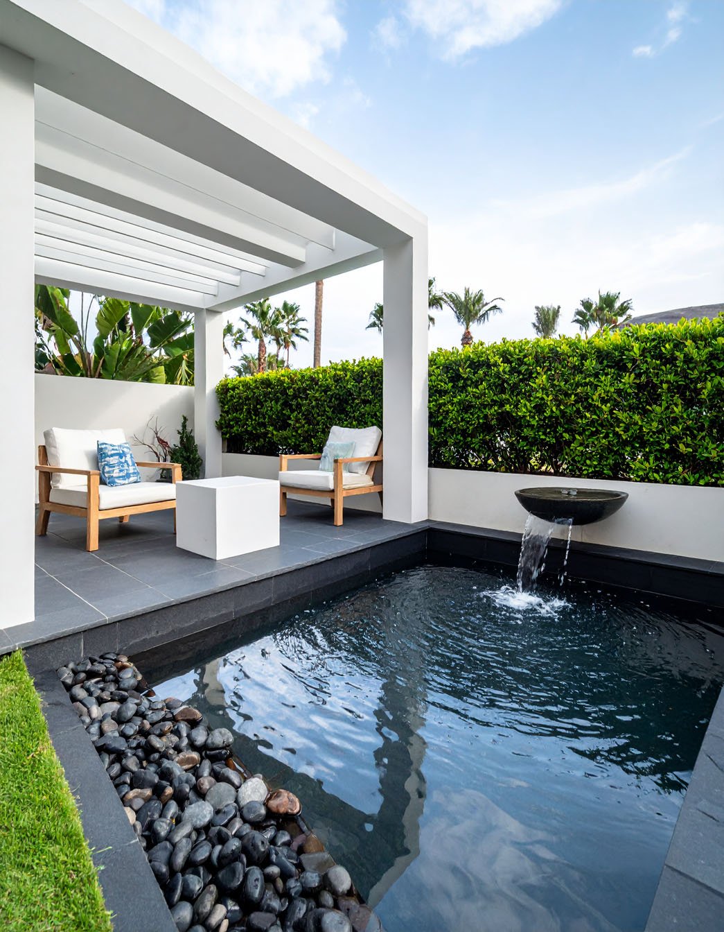 Patio avec bassin, fontaine et fauteuils sous pergola blanche