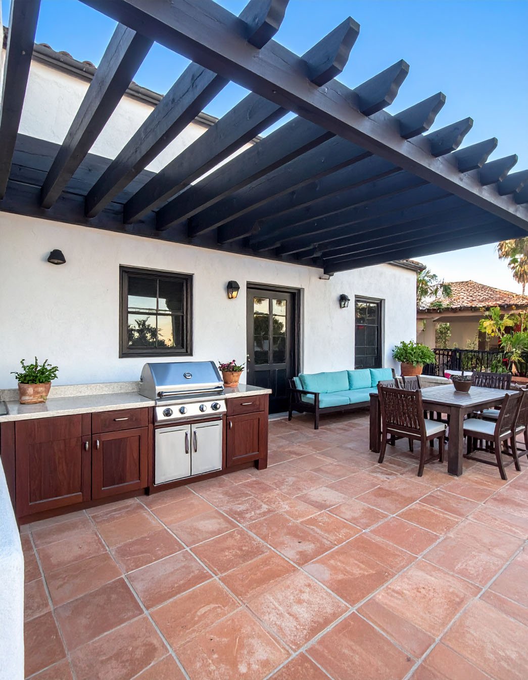 Terrasse avec cuisine extérieure, barbecue et coin repas sous pergola