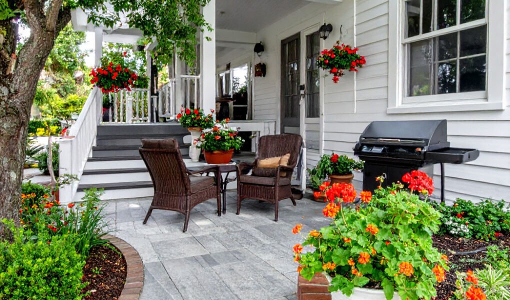 Patio fleuri avec salon de jardin en rotin et barbecue