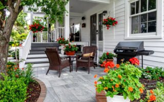 Patio fleuri avec salon de jardin en rotin et barbecue
