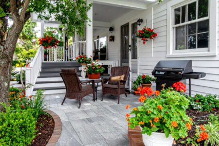 Patio fleuri avec salon de jardin en rotin et barbecue