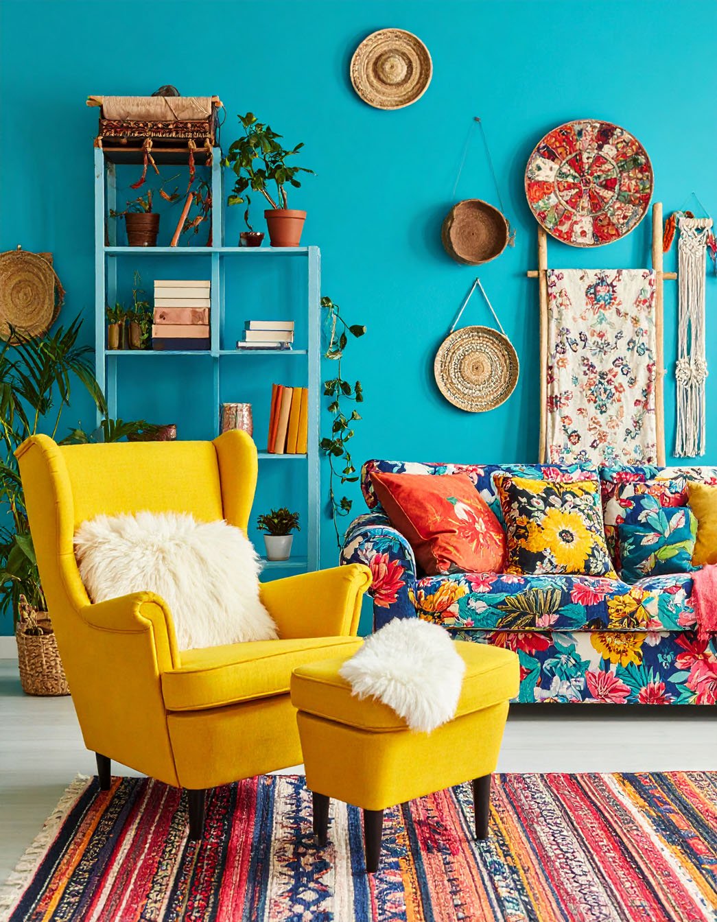 Salon bohème avec mur turquoise vif, fauteuil et ottoman jaunes, et canapé à motifs floraux