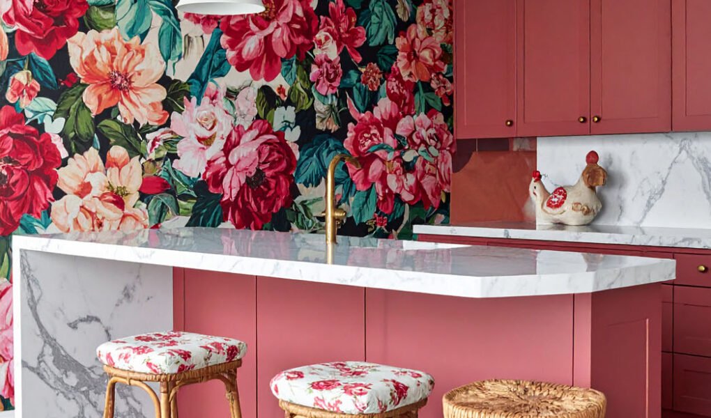 Cuisine audacieuse avec îlot rose corail, mur à grand motif floral et sol à damier