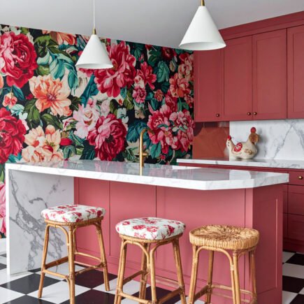 Cuisine audacieuse avec îlot rose corail, mur à grand motif floral et sol à damier