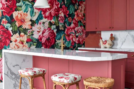 Cuisine audacieuse avec îlot rose corail, mur à grand motif floral et sol à damier