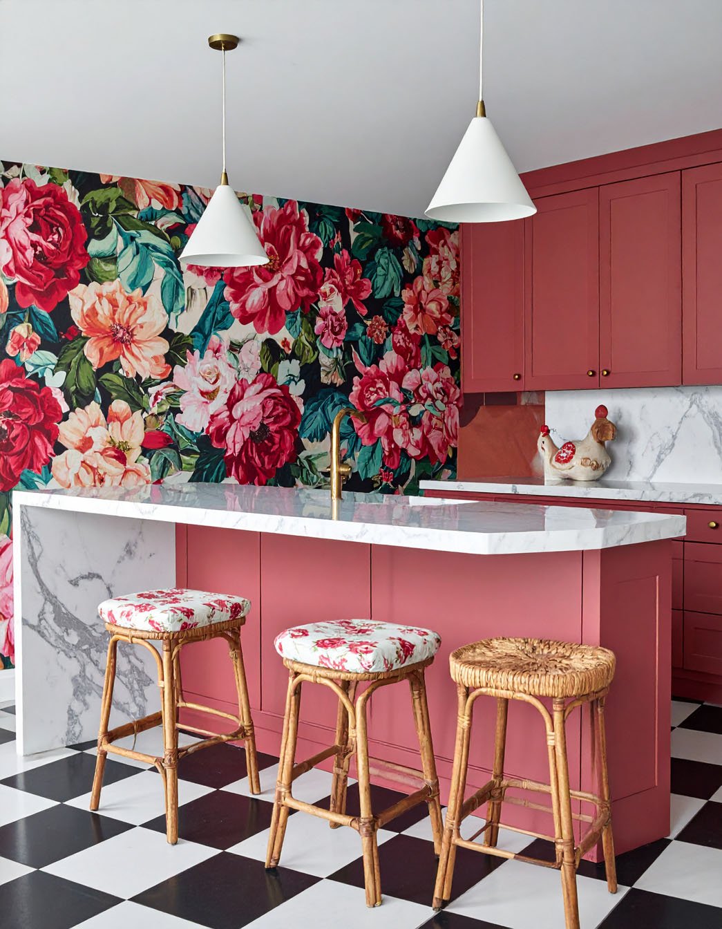 Cuisine audacieuse avec îlot rose corail, mur à grand motif floral et sol à damier