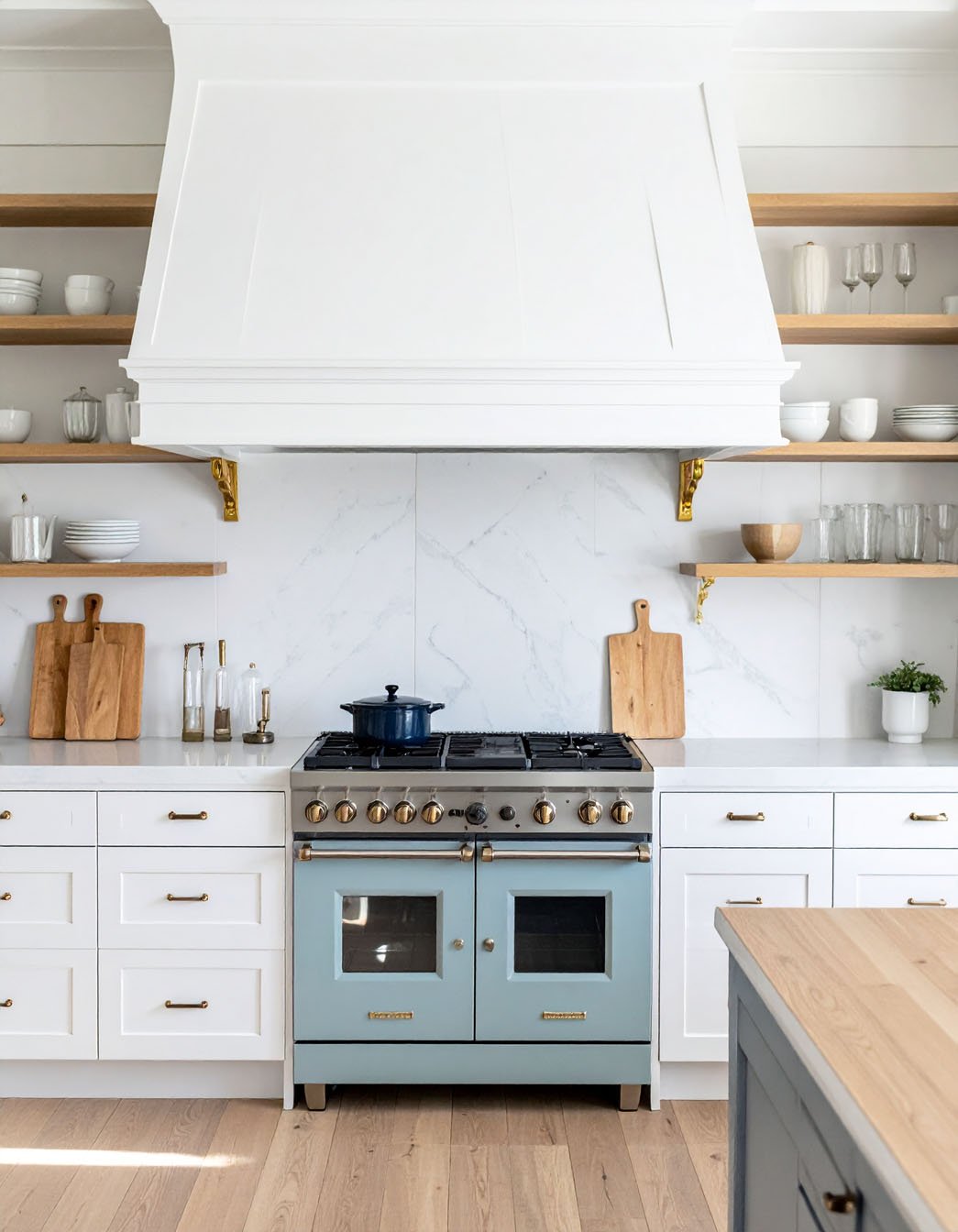Cuisine avec meubles blancs, piano de cuisson bleu pastel et étagères en bois