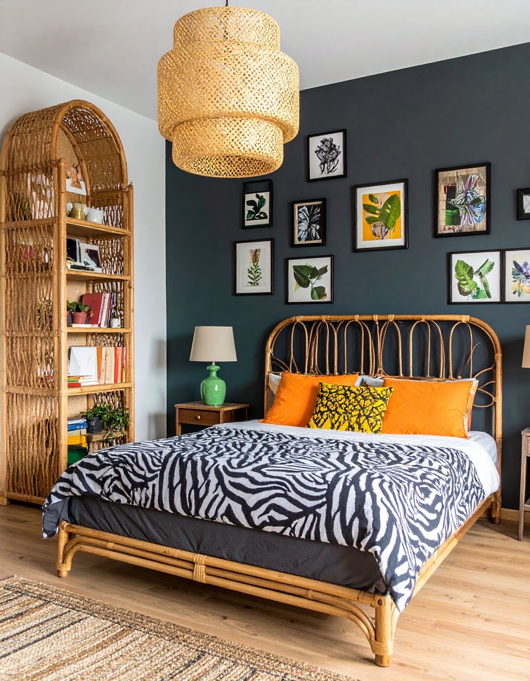 Chambre avec lit en rotin, parure à motif zèbre, coussins orange et étagère en rotin