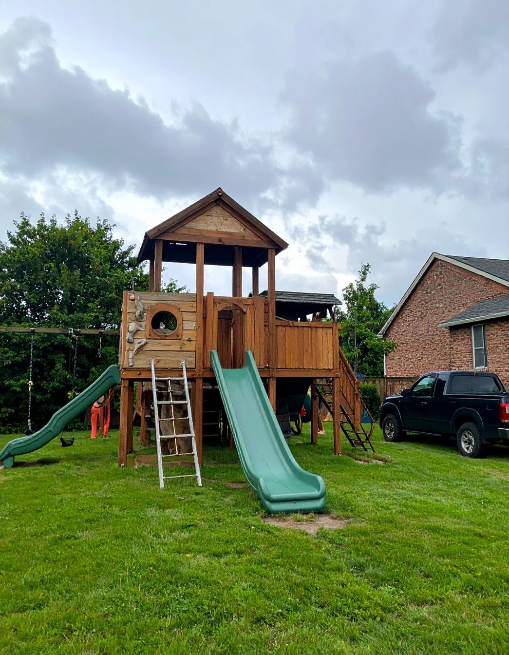 Jardin avec aire de jeux en bois pour enfants, toboggan et balançoires, et foyer extérieur