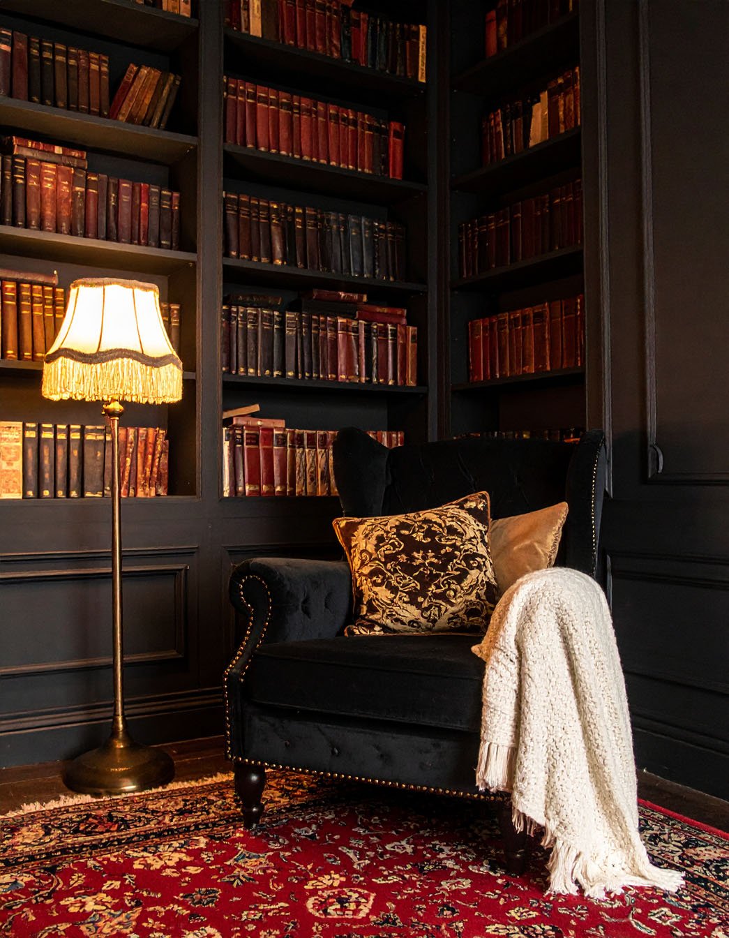 Salon avec murs gris, fauteuil en velours noir et tableau de nature morte