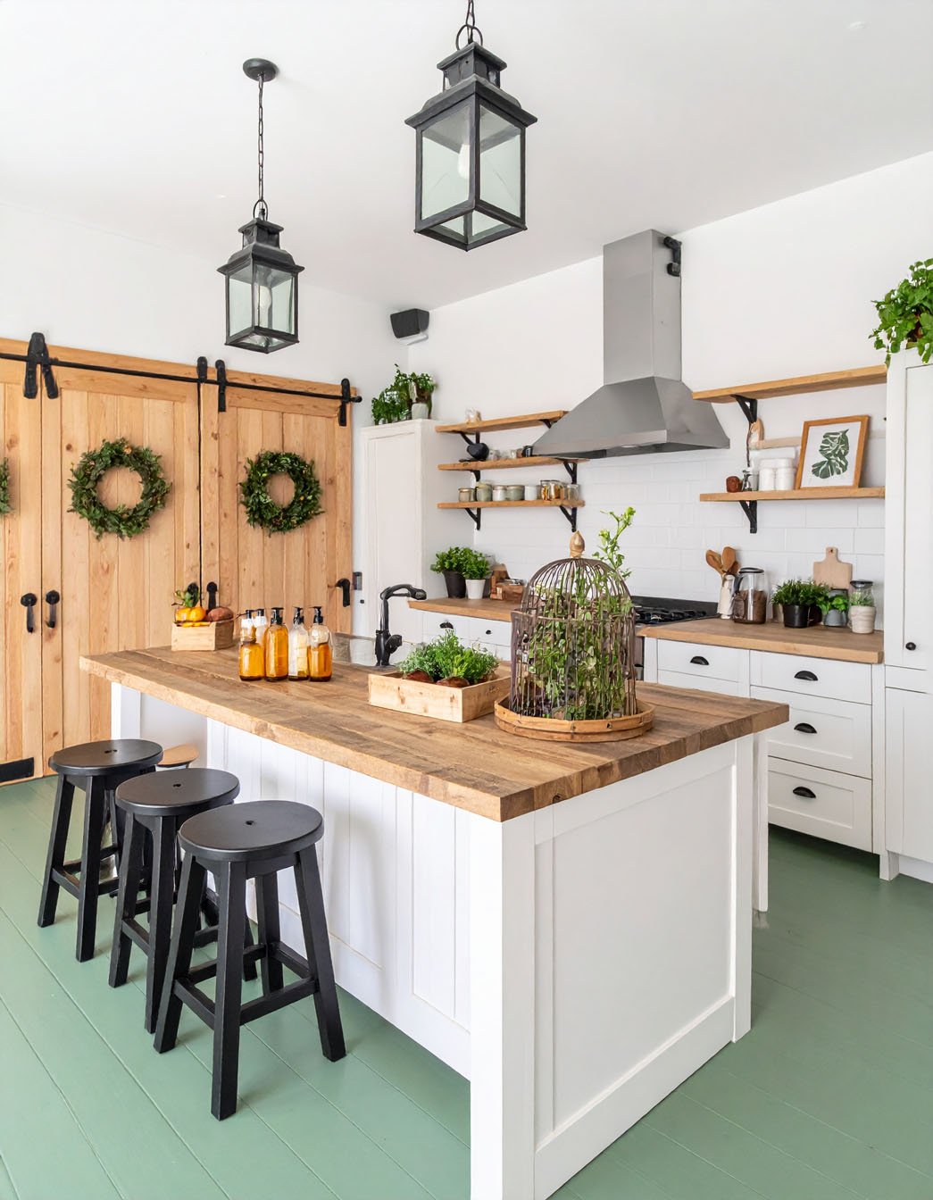 Cuisine de ferme moderne avec îlot en bois, tabourets noirs et sol vert menthe