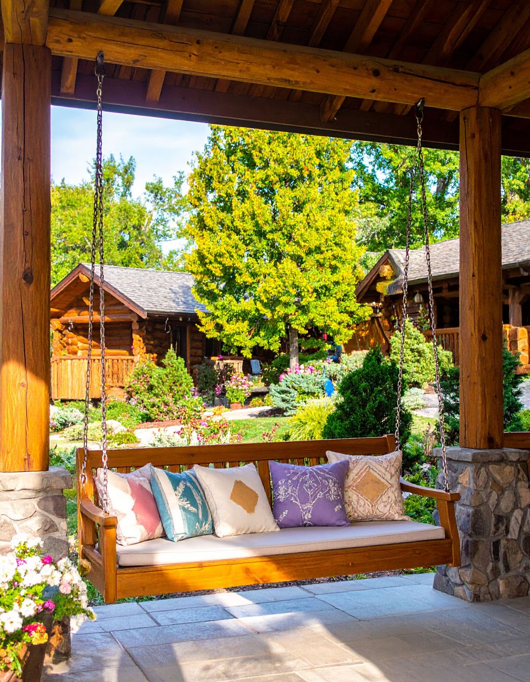 Balancelle en bois sur un porche rustique avec vue sur jardin et chalets