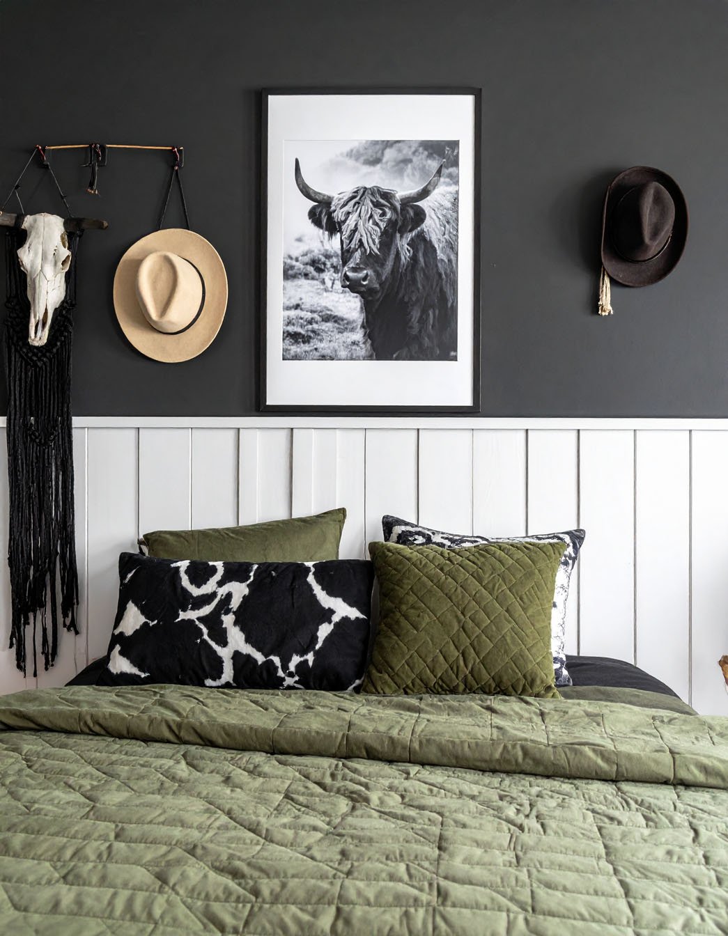 Chambre avec mur d'accent noir, literie vert olive et décorations murales de style western