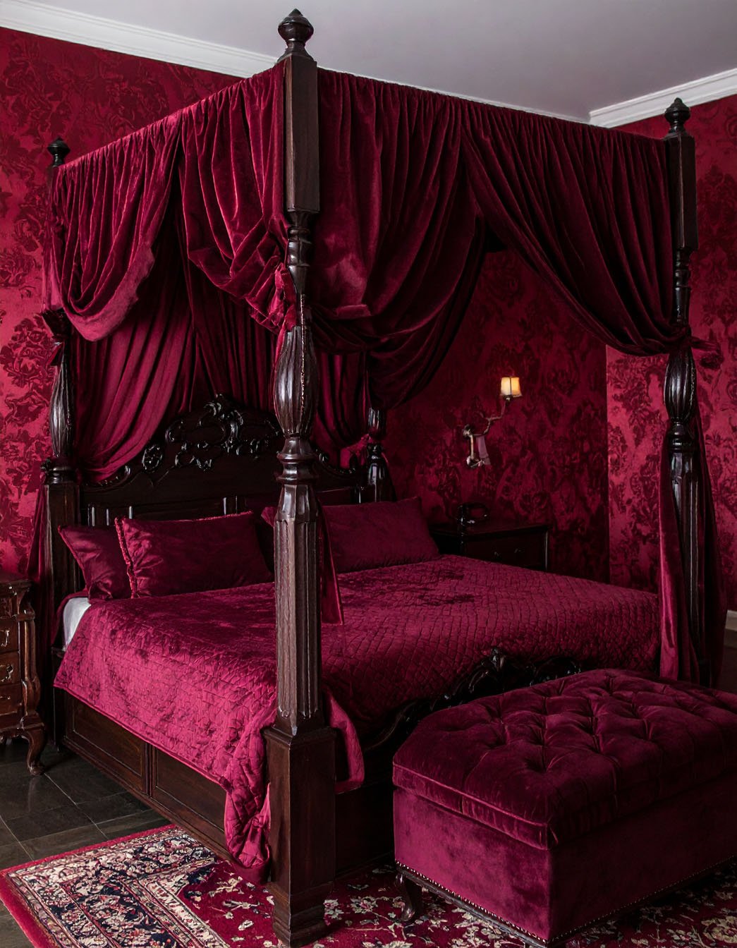 Chambre de style gothique avec lit à baldaquin noir, murs gris et chandelier