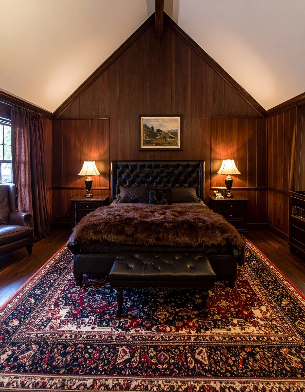 Chambre avec lit à baldaquin en fer forgé noir, murs gris et poutres apparentes