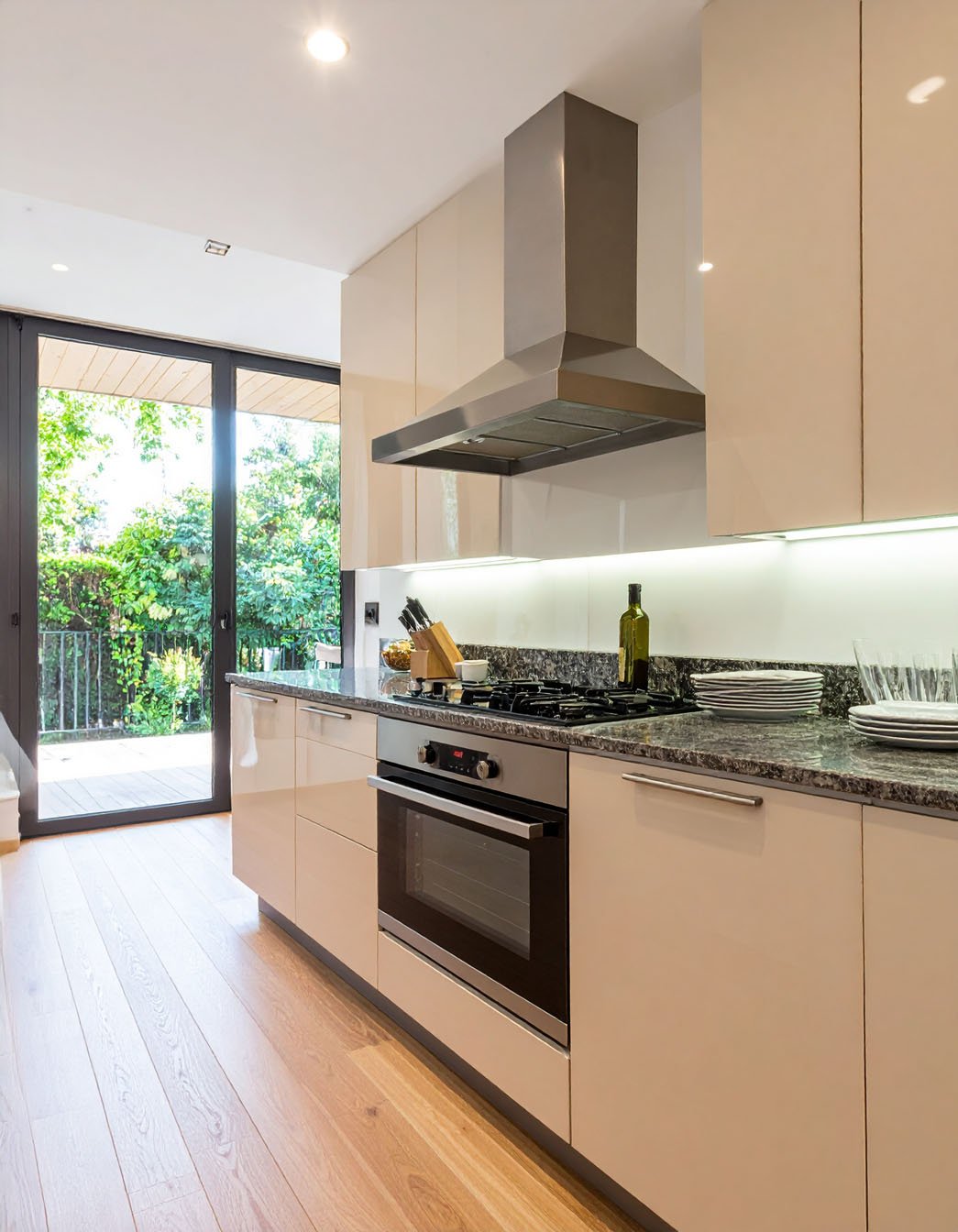 Cuisine moderne avec meubles beige laqué, plans de travail en granit et baie vitrée