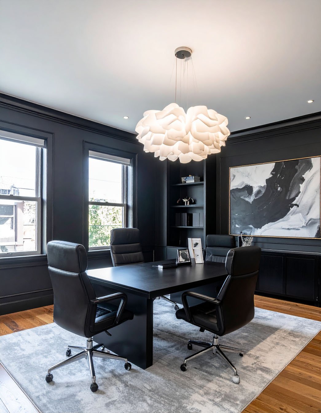 Bureau sombre avec murs noirs, bureau en bois foncé et fauteuil de direction en cuir