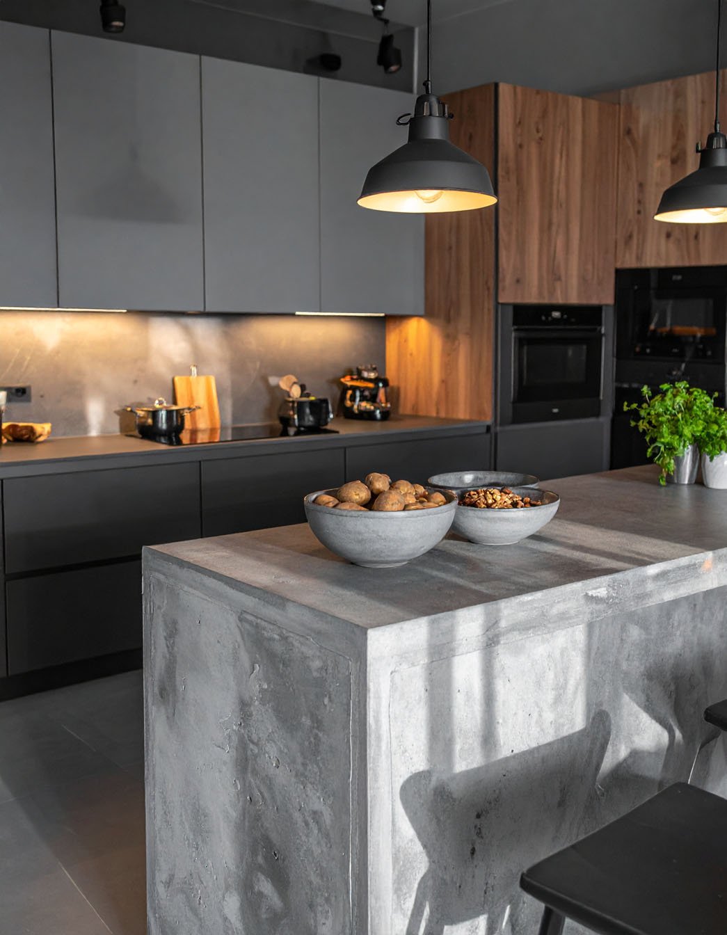 Cuisine industrielle avec îlot en béton ciré, meubles gris mat et éléments en bois