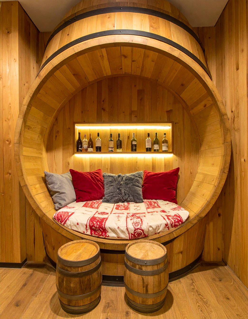 Chambre rustique avec lit rond intégré dans un grand tonneau en bois et murs en pierre