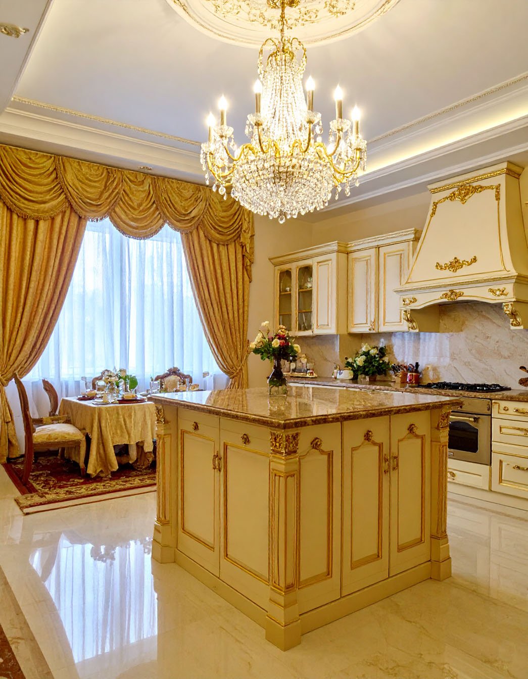Cuisine et salle à manger luxueuses, tons crème et or, îlot central et lustre en cristal