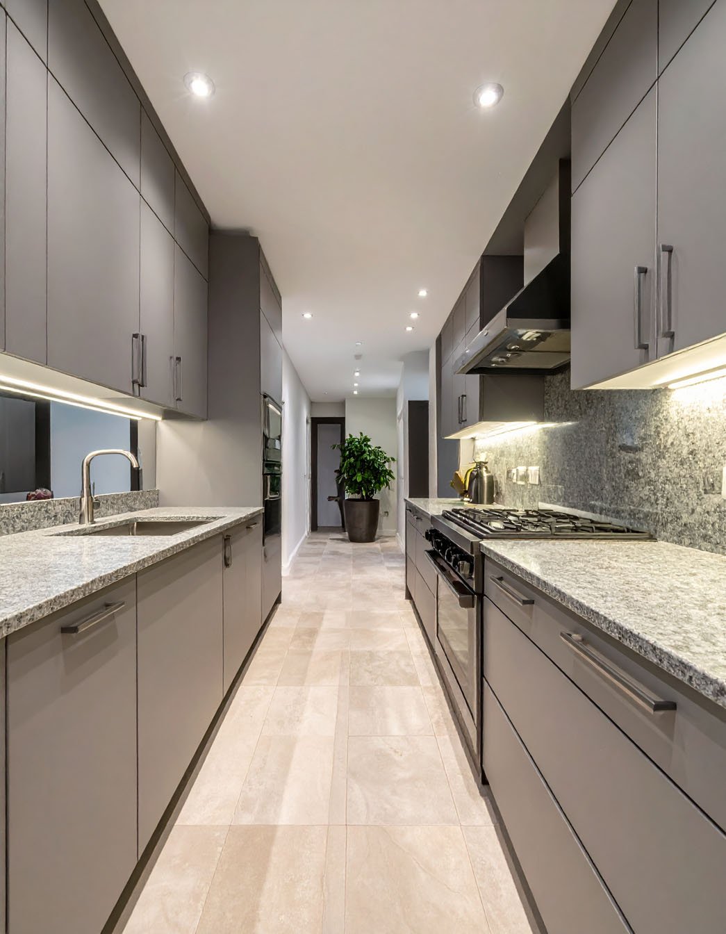 Longue cuisine grise avec plans de travail en granit et sol carrelé beige
