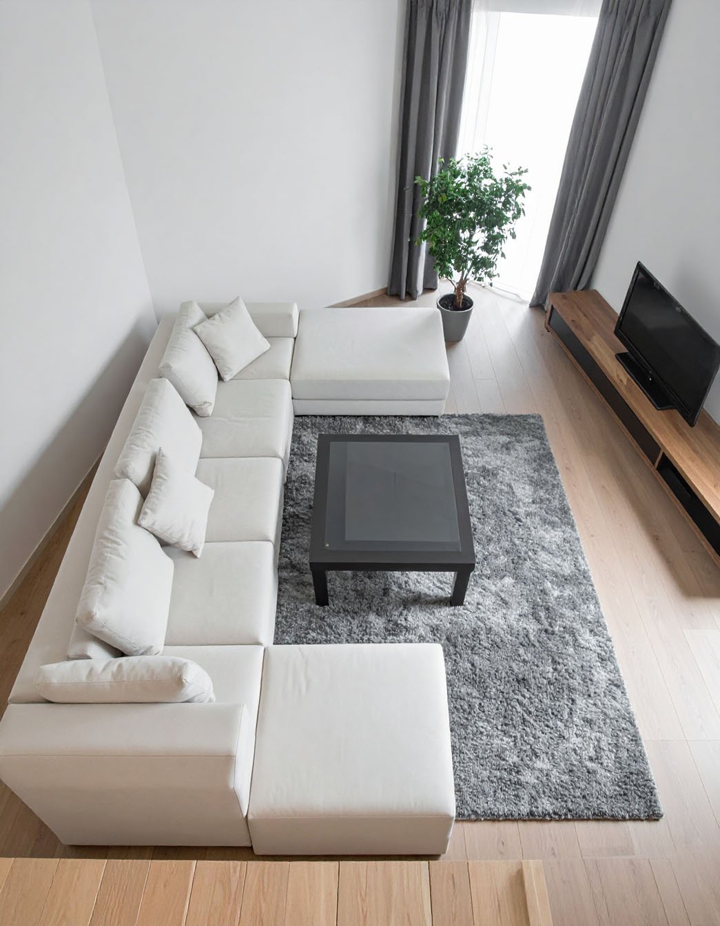 Salon d'angle avec grand canapé sectionnel blanc, tapis gris et vue plongeante