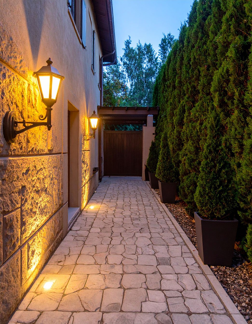 Chemin de jardin en dalles de pierre éclairé par des bornes lumineuses la nuit