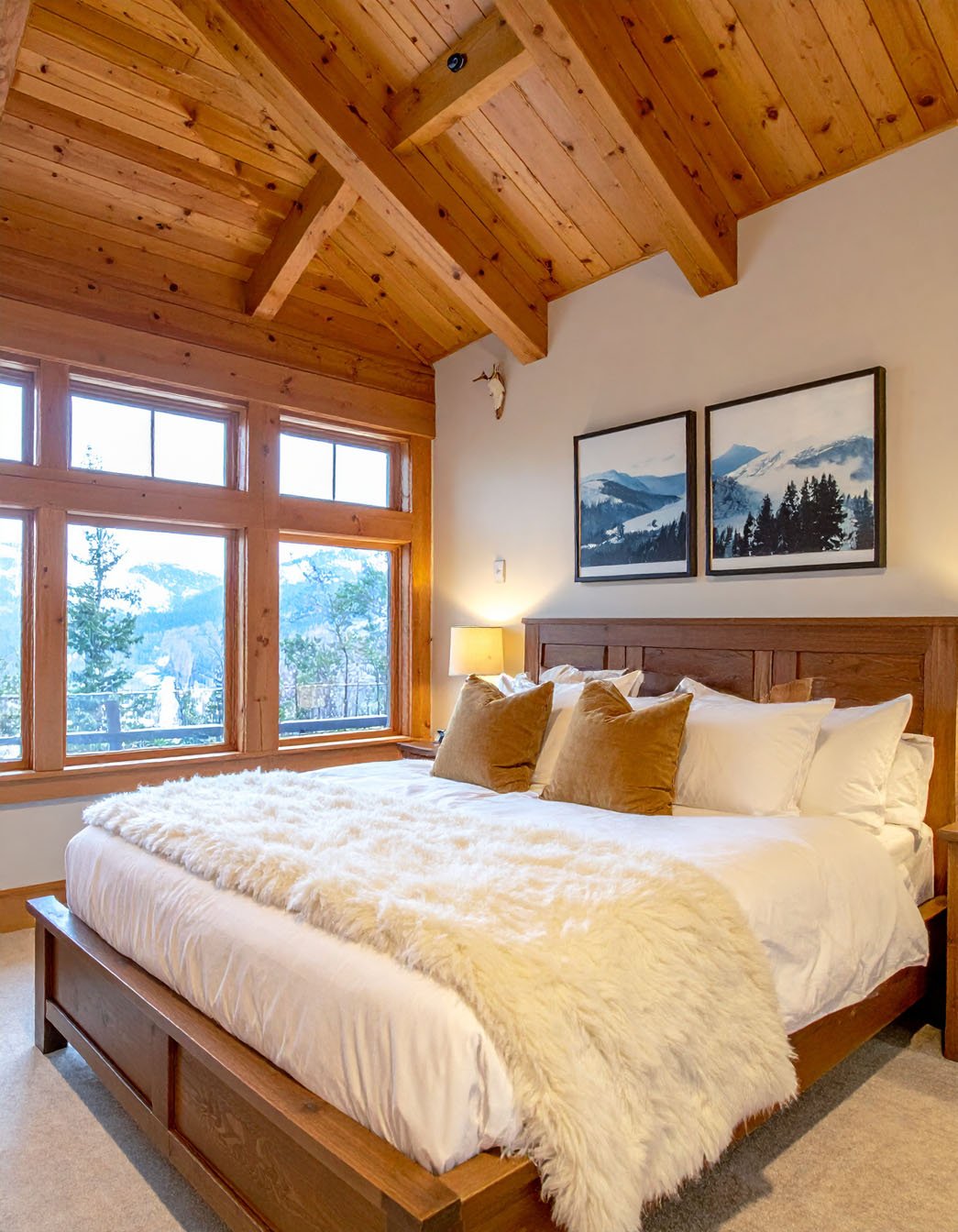 Chambre avec lit en bois clair, literie blanche, murs beiges et grand tapis à motifs
