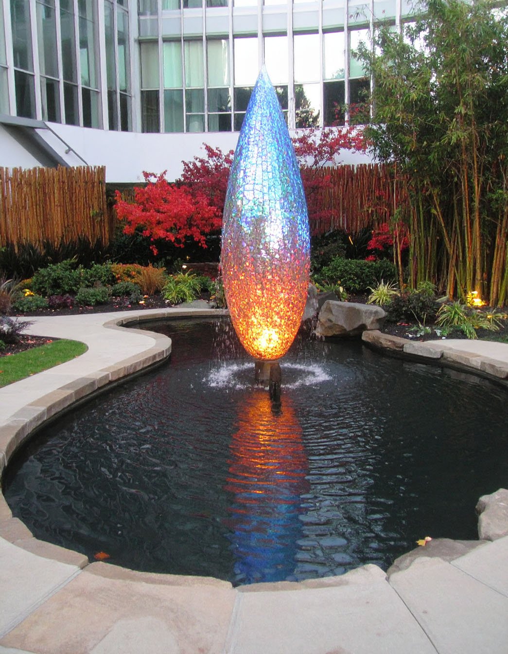 Allée de jardin éclairée par des bornes lumineuses sphériques colorées la nuit