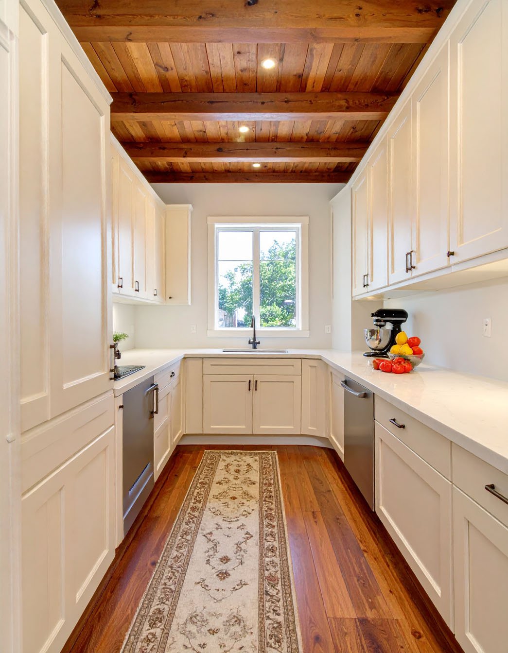 Cuisine en U blanche avec plafond en lattes de bois et long tapis à motifs
