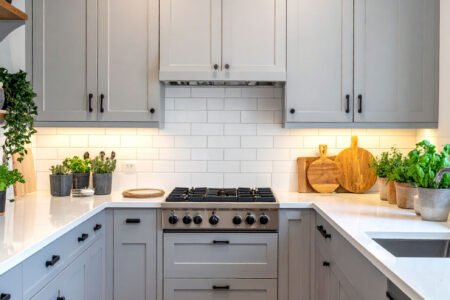 Cuisine en U avec meubles gris clair, crédence en carrelage métro blanc et tapis à motifs