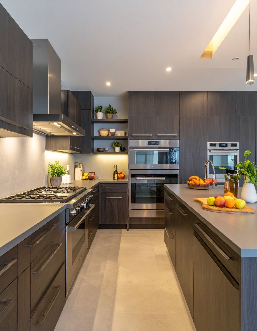 Cuisine moderne avec meubles en bois foncé, îlot avec plan de travail gris et appareils inox