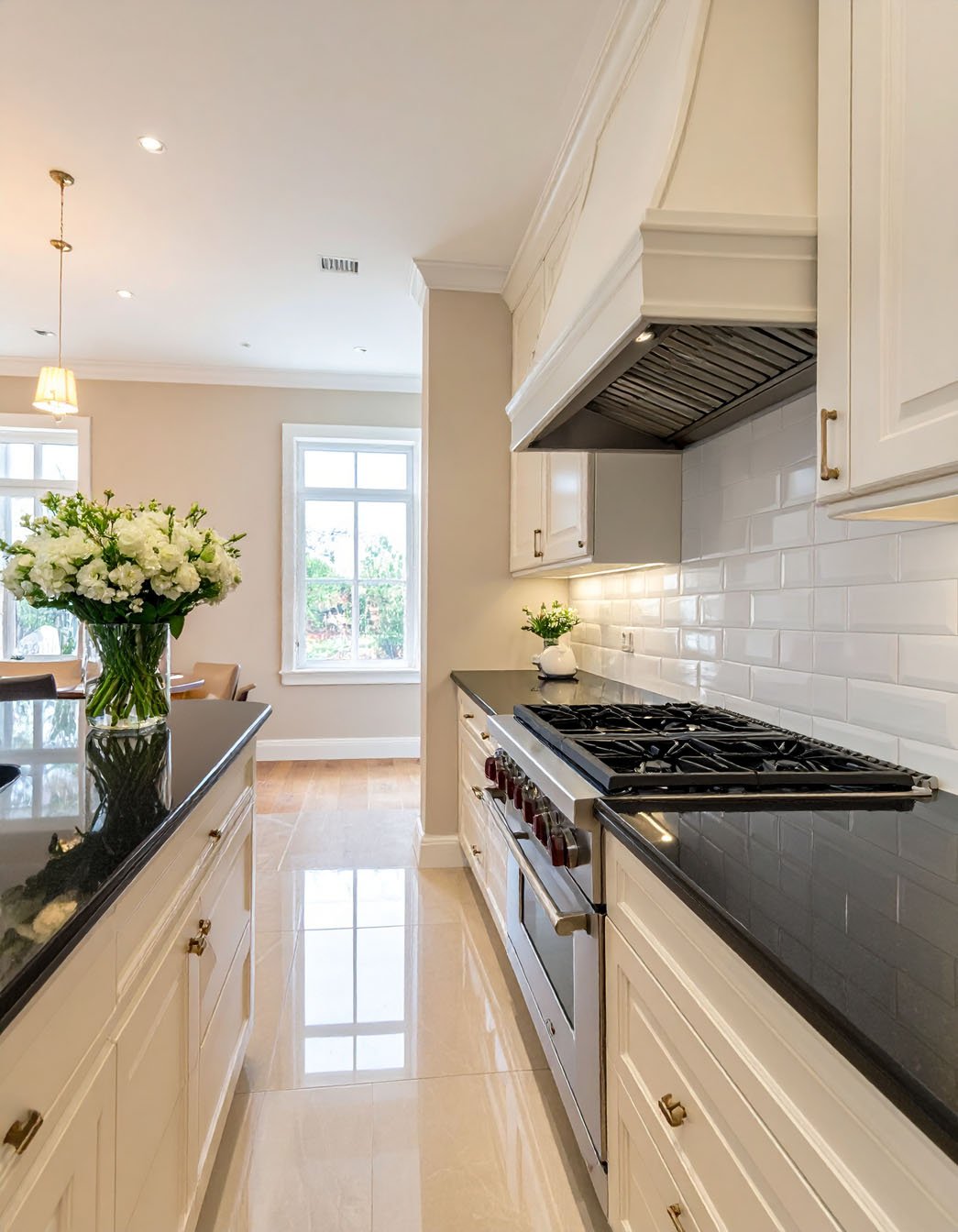 Cuisine blanche avec plans de travail noirs, crédence en carrelage métro et sol brillant