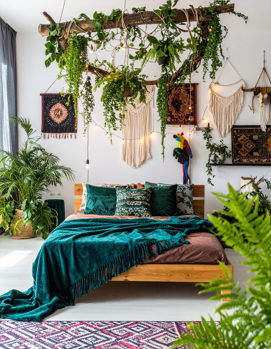 Chambre bohème avec lit en bois, tentures murales, et une profusion de plantes suspendues et au sol