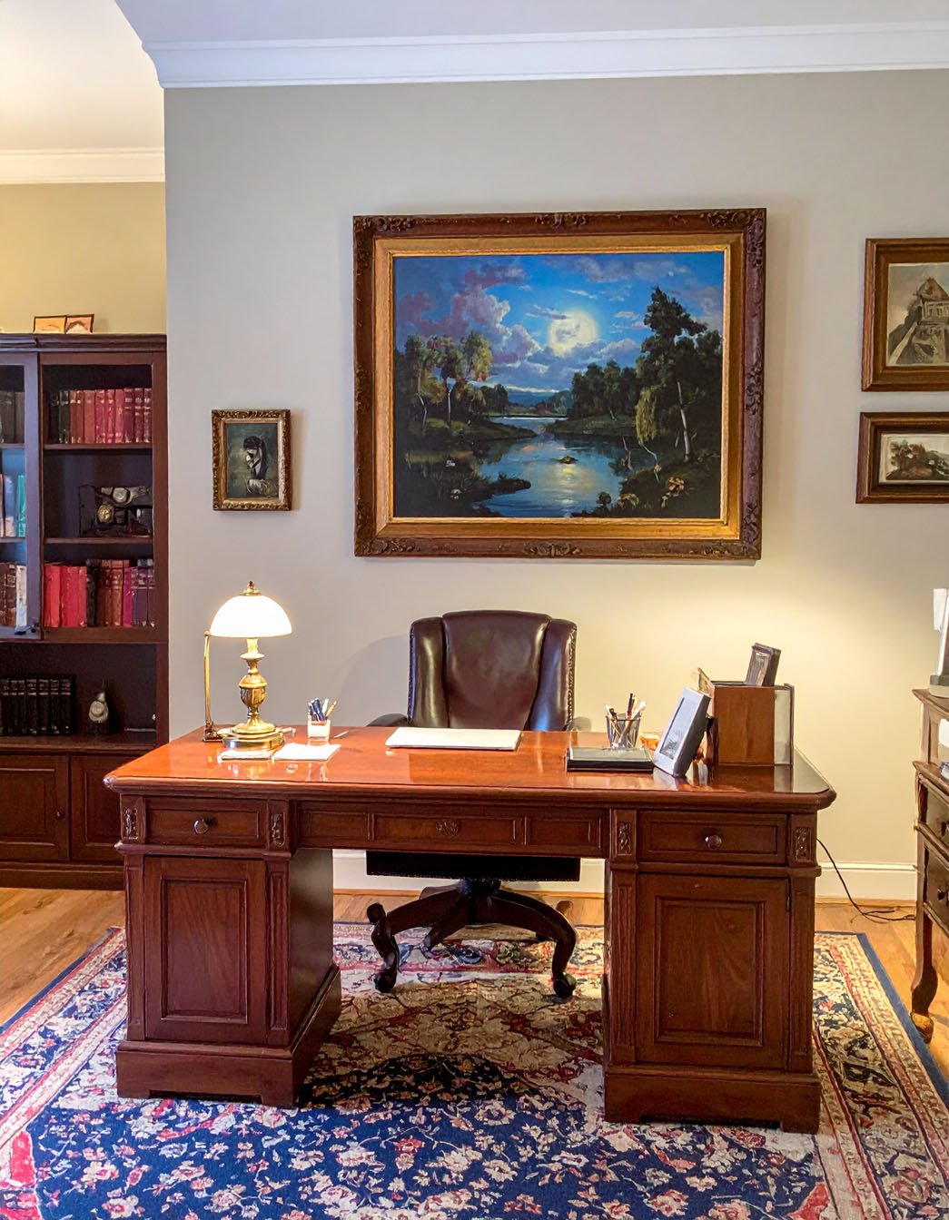Bureau classique avec grand bureau en bois massif, fauteuil en cuir et tableau de paysage