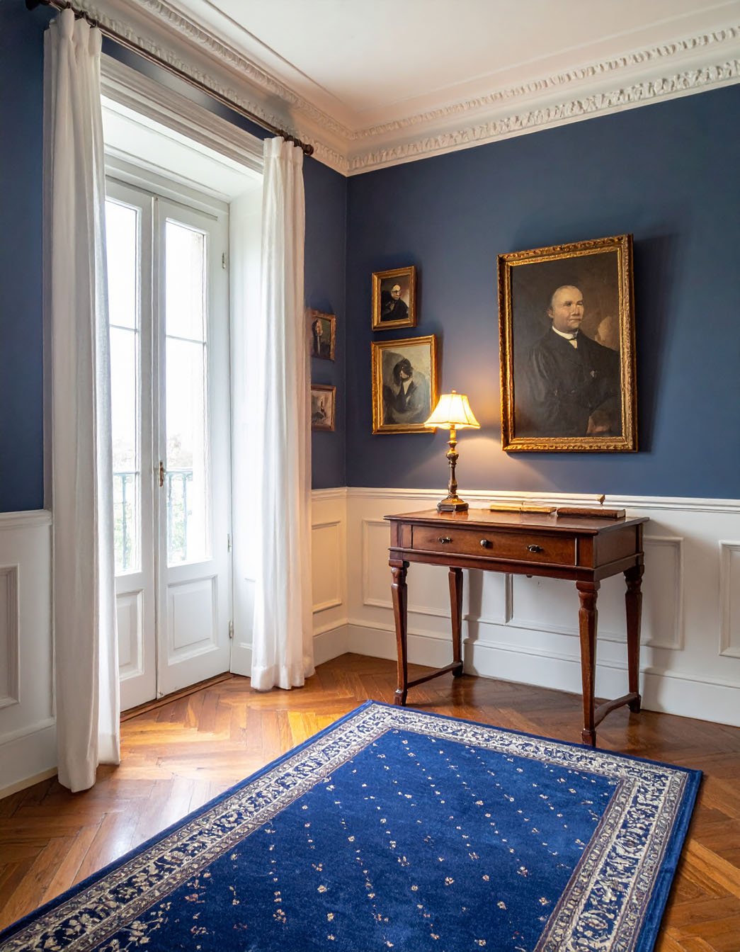 Coin de pièce avec murs bleus, bureau en bois et tapis bleu à motifs