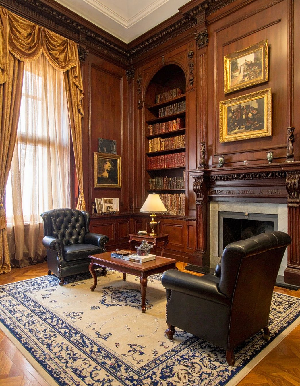 Bureau lambrissé en bois sombre avec fauteuils en cuir noir et tapis à motifs