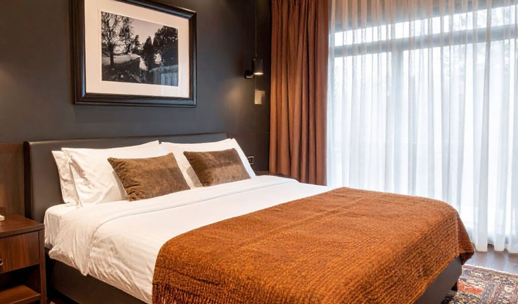 Chambre avec murs foncés, plafond en lattes de bois, plaid couleur rouille et tapis persan