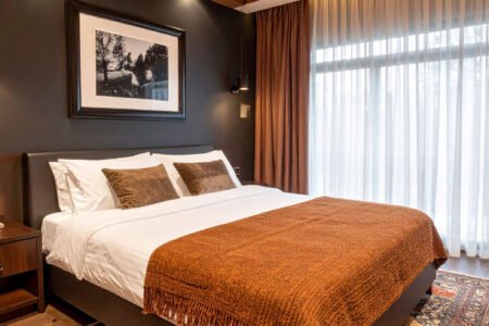 Chambre avec murs foncés, plafond en lattes de bois, plaid couleur rouille et tapis persan