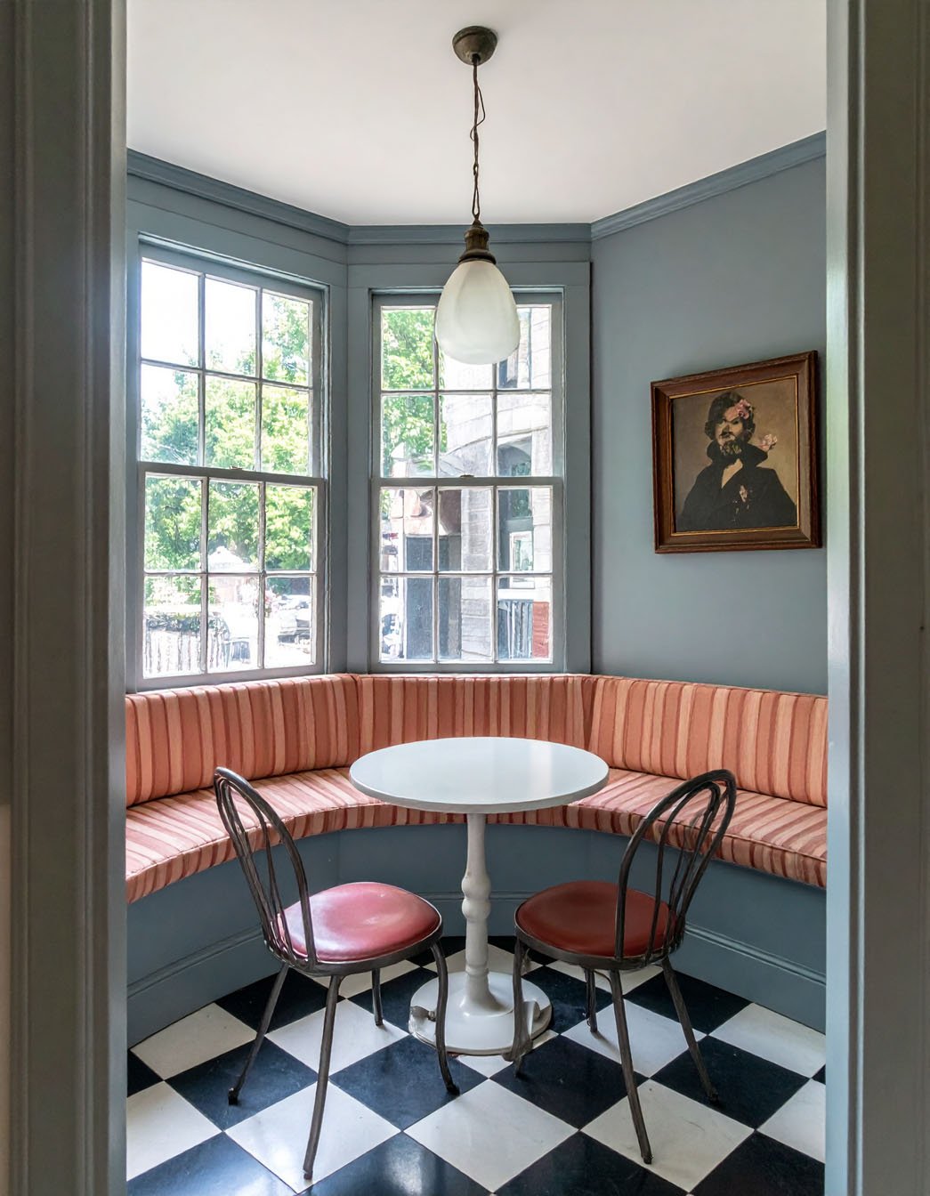 Coin repas d'angle avec banquette rayée, table ronde et sol à damier noir et blanc