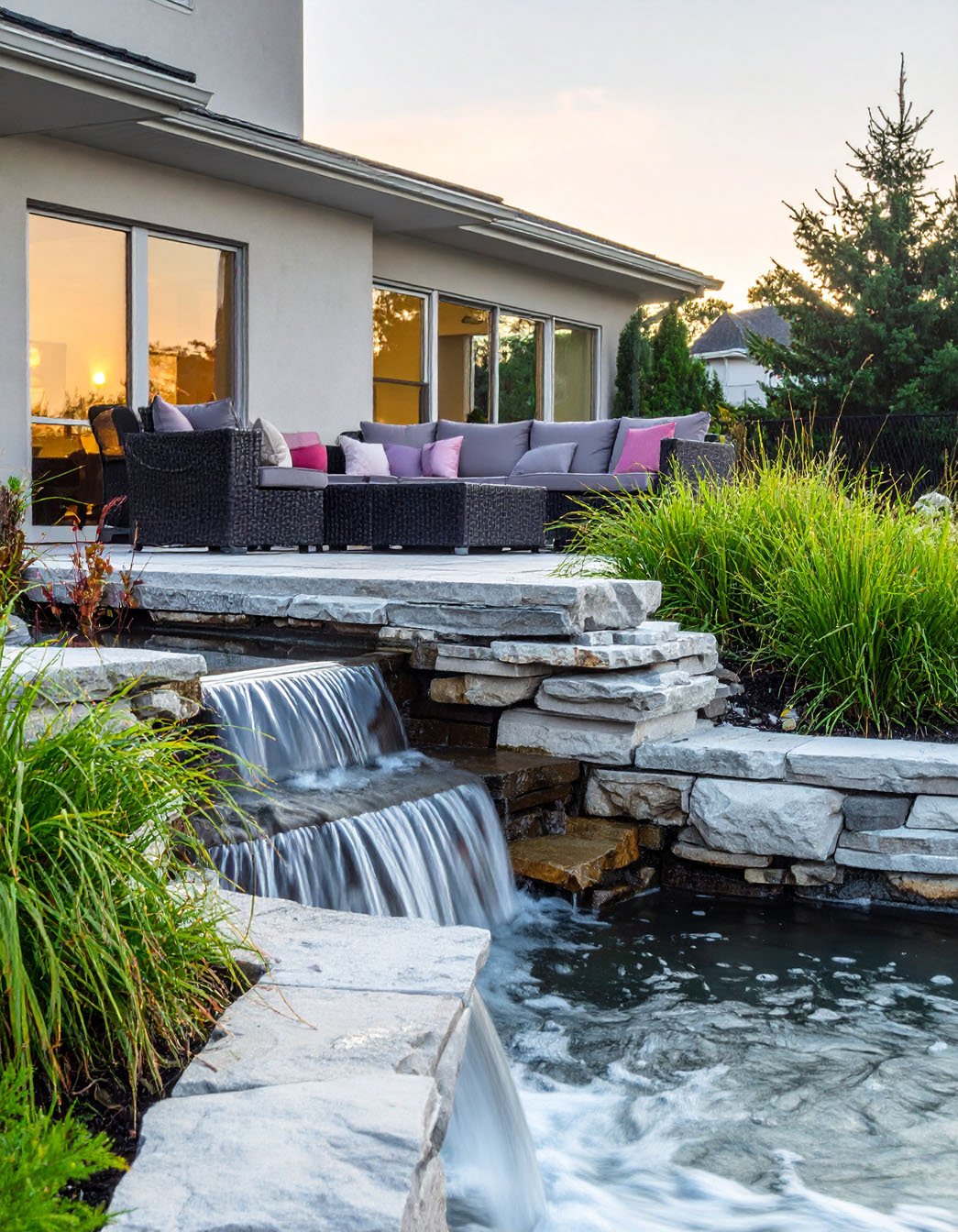 Terrasse avec salon de jardin et cascade d'eau en pierre en contrebas