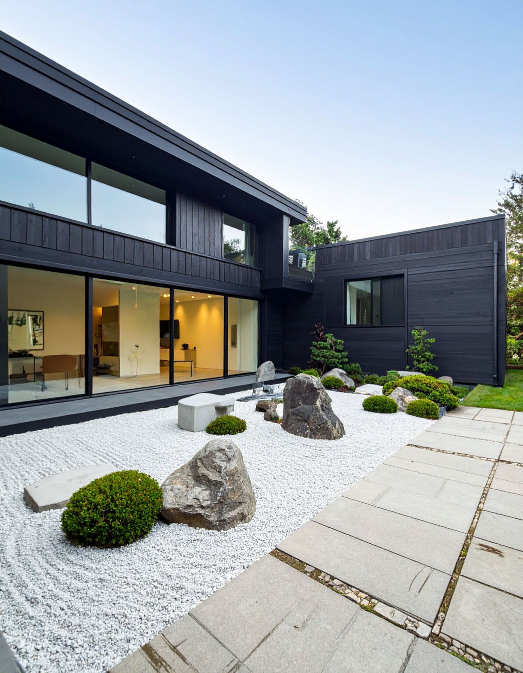 Villa moderne avec revêtement sombre, grandes baies vitrées et éclairage extérieur