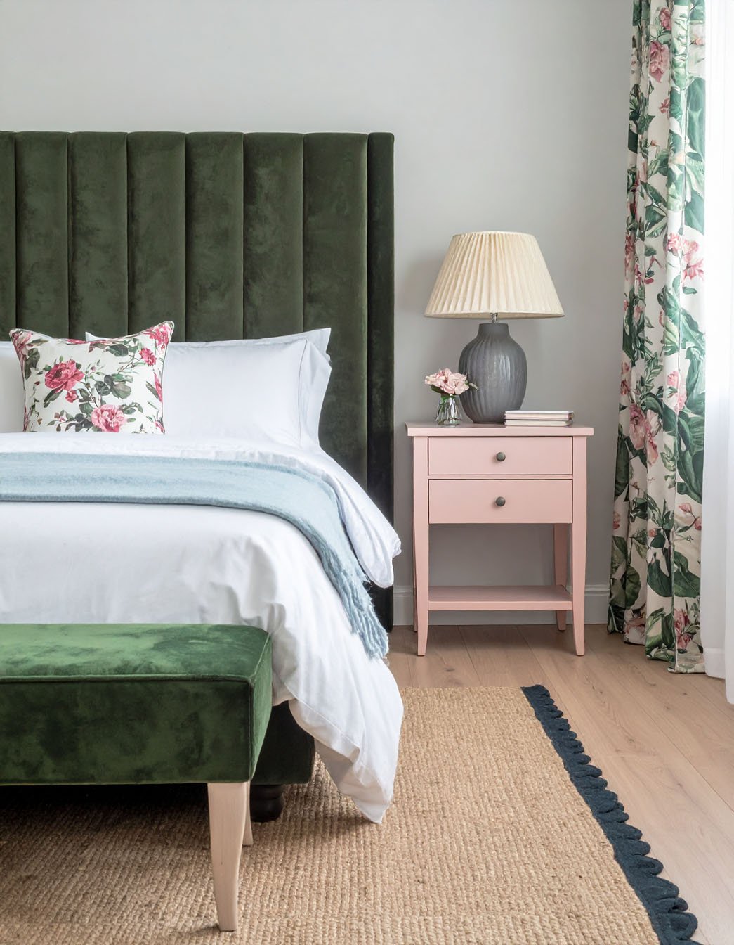 Chambre avec tête de lit haute en velours vert, banc assorti et table de chevet rose