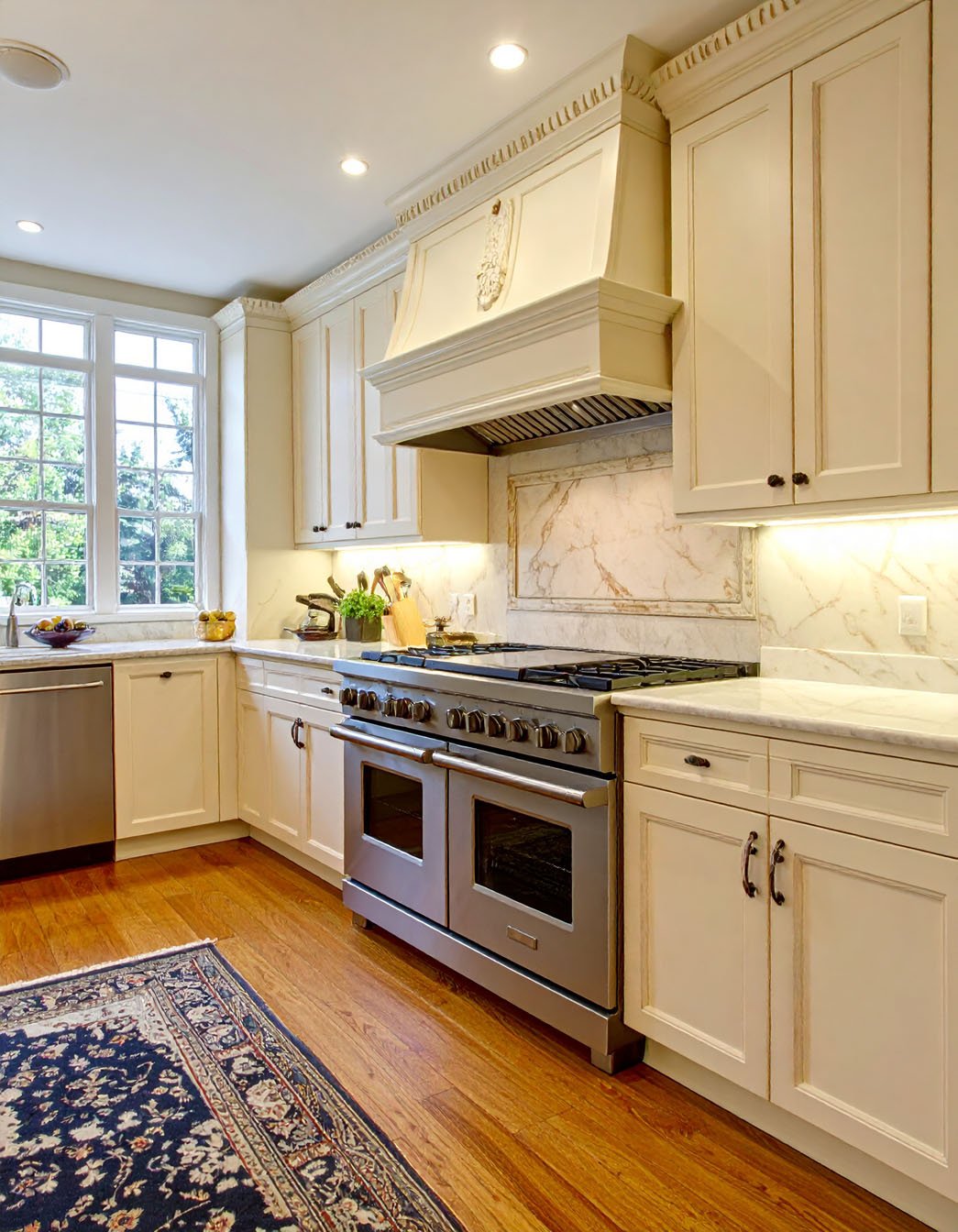 Cuisine classique avec meubles blanc cassé, hotte décorative et tapis persan