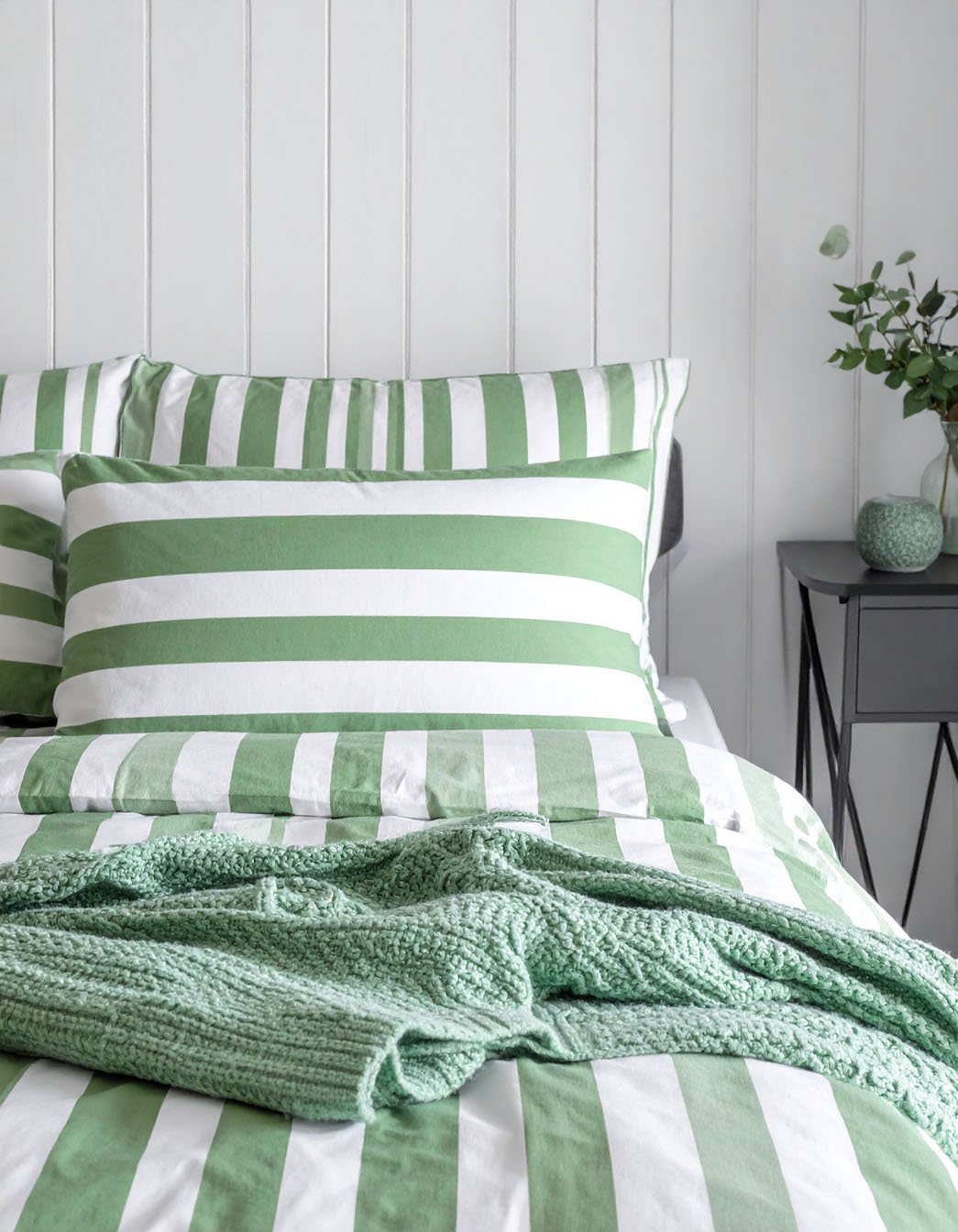 Lit avec parure à rayures vertes et blanches et plaid en tricot vert sauge