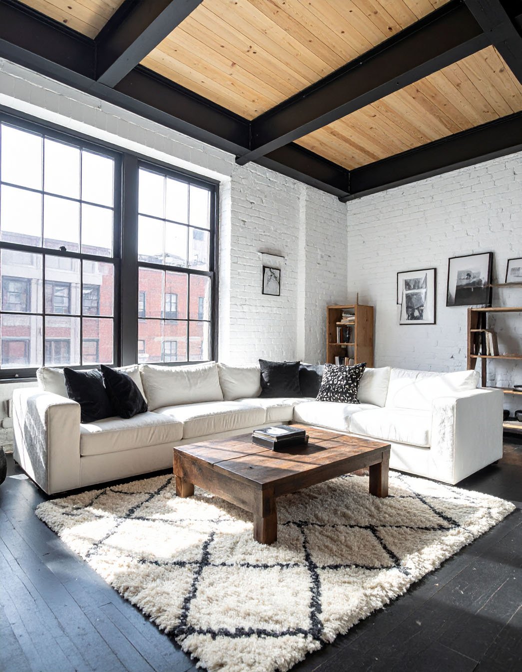 Salon de style loft avec murs en briques blanches, grand canapé blanc et tapis texturé